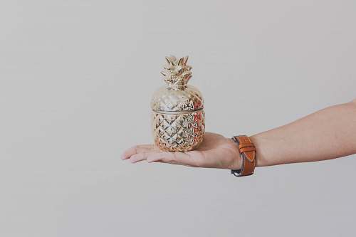 human person holding gold-colored pineapple design rack wristwatch
