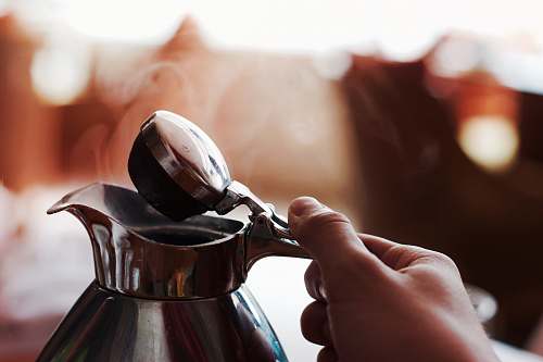 human person holding silver teapot coffee