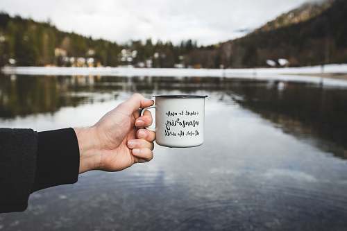 human person holding white ceramic mug cup