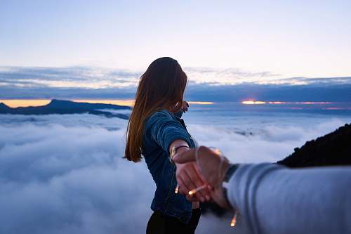 people person holding woman's hand on top of hill couple