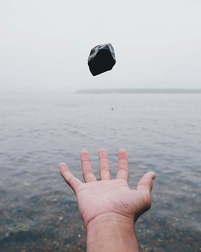 human person throwing black stone on water hand