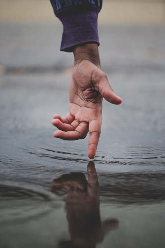 human person touching body of water and creating ripples finger