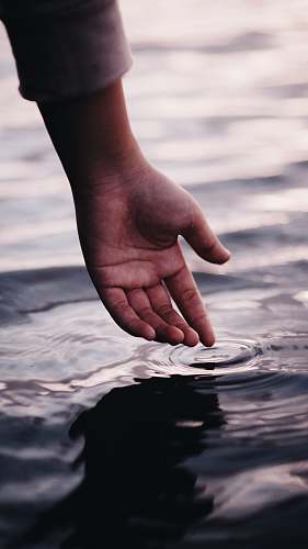 human person touching body of water water