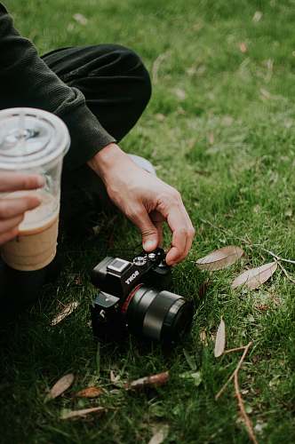human person using black Sony SLR camera on green grass field camera