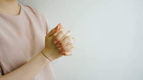 hand person wearing pink crew-neck shirt with hand clasped together pink shirt