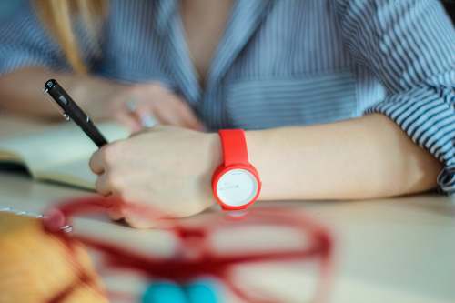 human person wearing red analog watch holding twist pen hand