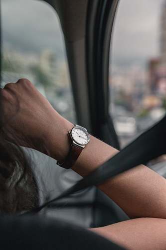 human person wearing round silver-colored analog watch with leather band wristwatch