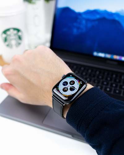human person wearing silver aluminum case Apple Watch with black Sport Band wristwatch
