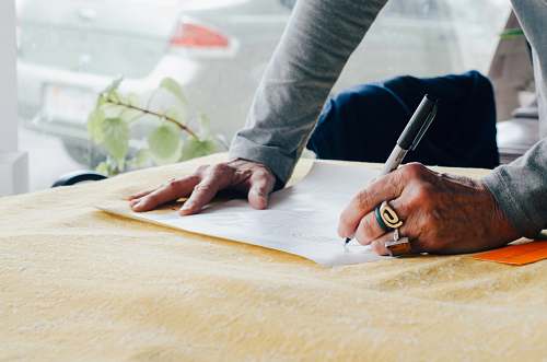 human person writing on white plain paper on the table photography people