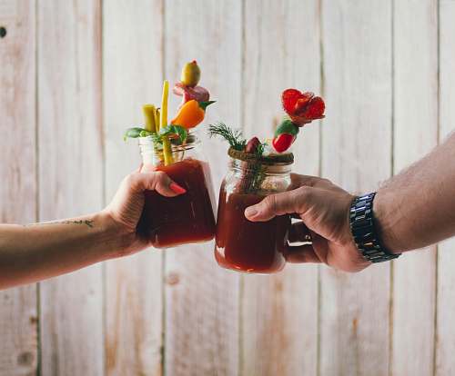 human two person holding filled clear glass jars drink