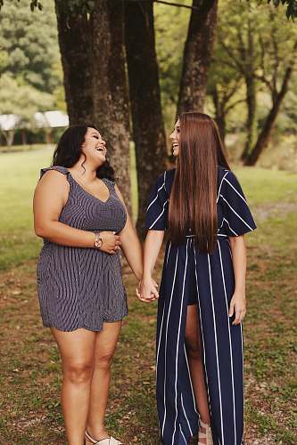 human two women laughing standing near tree apparel