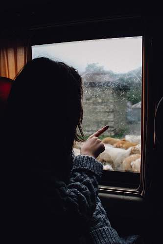 people woman in gray knitted sweater looking and pointing at the window girl