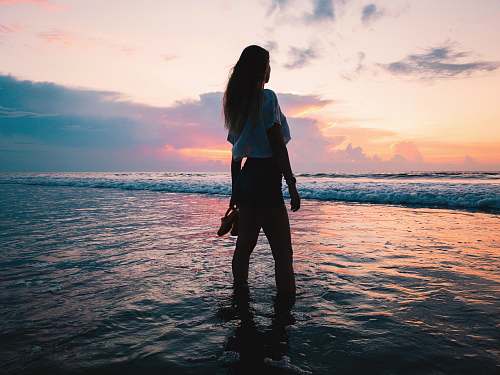 human woman in white shirt and shorts on sea water standing