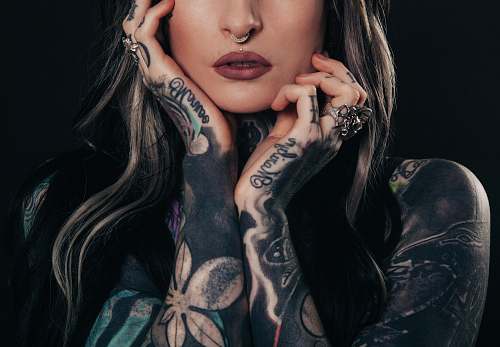 people woman showing body tattoo while holding her face tattoo