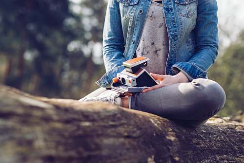 human woman sitting on log holding camera and book people