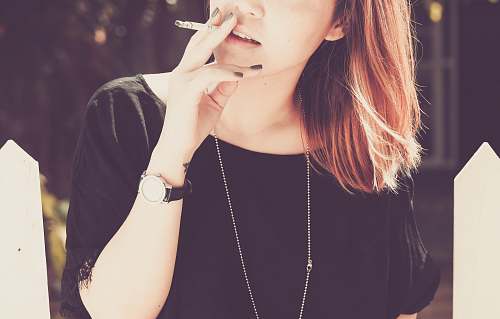 people woman smoking beside white fence human