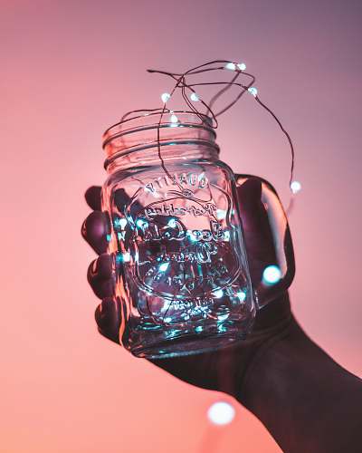 light person holding clear glass mason jar with strip lights inside glass