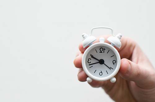 timepiece person holding white mini bell alarmclock holding