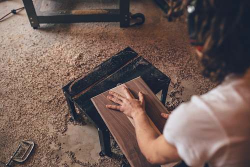 wood person touching brown plank sanding