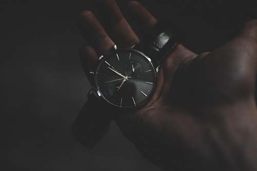 gold person holding watch pointing at 6:17 clock
