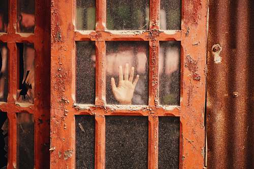 rust person hand on glass panel door with red wooden frame door