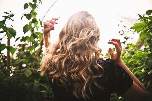 hair blonde haired woman in black top surrounded by tall plants blonde