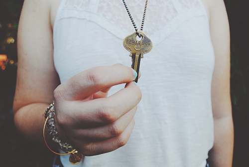 key person holding gold-colored key pendant fearless