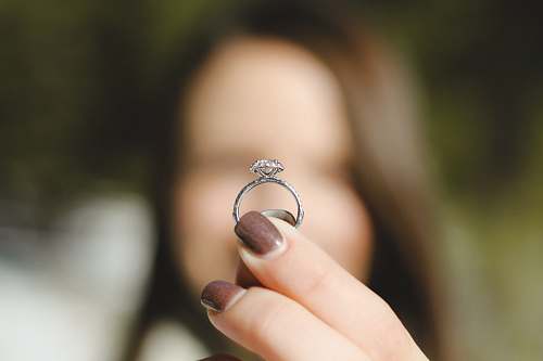 hand shallow focus photography of woman holding a diamond ring ring
