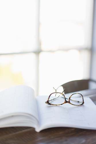 accessory brown framed eyeglasses on top of open book glasses