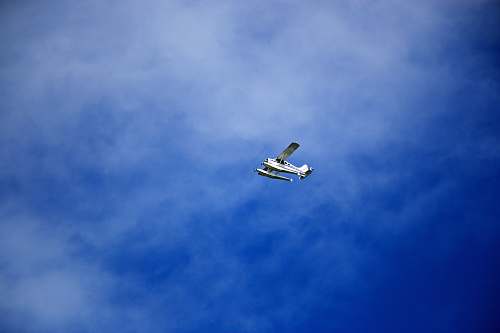 aircraft white flying biplane during white and blue sky seaplane