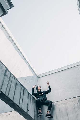 clothing man sitting by ledge of building during daytime human