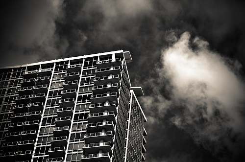 building grayscale photography of building under cloudy sky urban