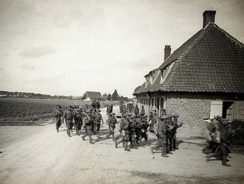 military grayscale photo of men standing beside houses military uniform