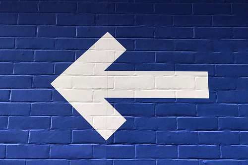 blue white arrow painted on brick wall sign