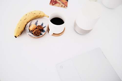 food white ceramic mug beside yellow banana flower fruit