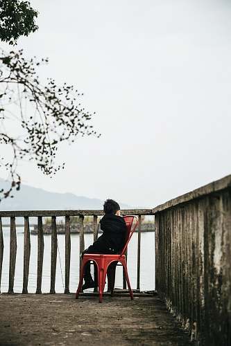 handrail boy sitting on armless chair beside baluster railing