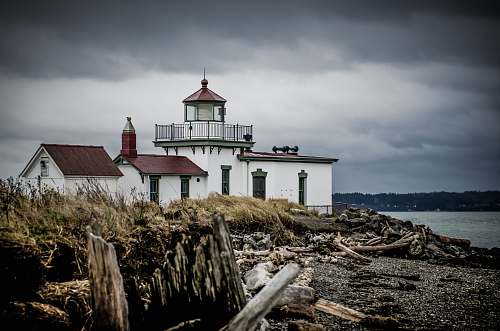 lighthouse white and brown house beside body of water house