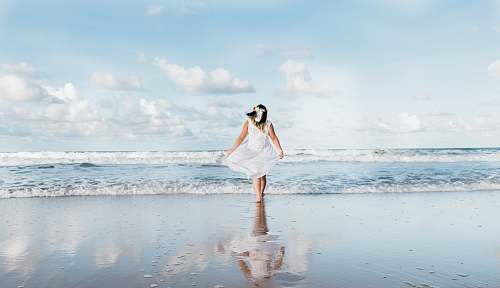 ocean woman in white dress walking on shore at daytime sea