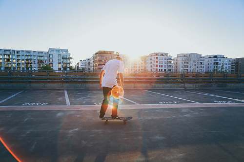 germany man riding skateboard on parking lot near buildings during golden hour skate