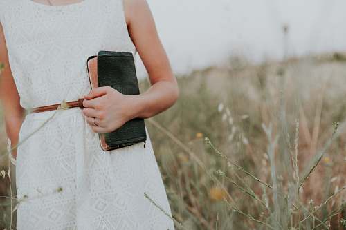 woman woman in white sleeveless dress holding book church