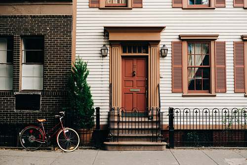 bicycle red bicycle parked beside black metal gate in front house home