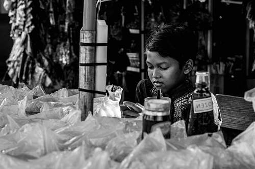 human boy sitting near table looking down person