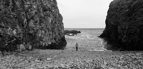 outdoors gray-scale photo of man near body of water rock