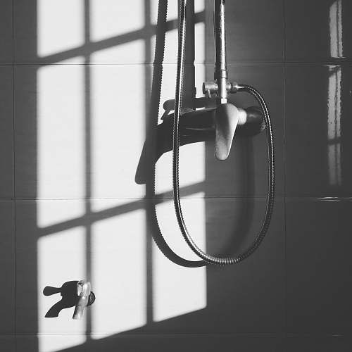 pole gray stainless steel shower head hanged on wall during daytime shower
