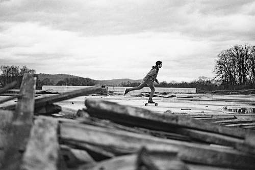 person grayscale photo of a man skateboarding outdoor wood
