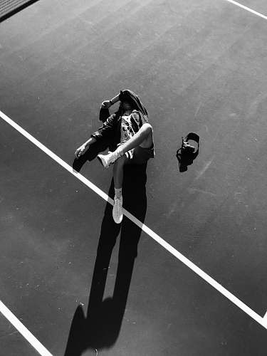 human grayscale photo of athlete lying down on court person