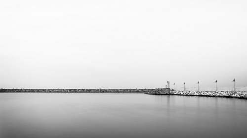 water grayscale photo of body of water near poles waterfront