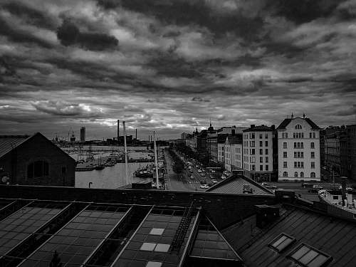 nature grayscale photo of buildings near body of water under cloudy sky weather