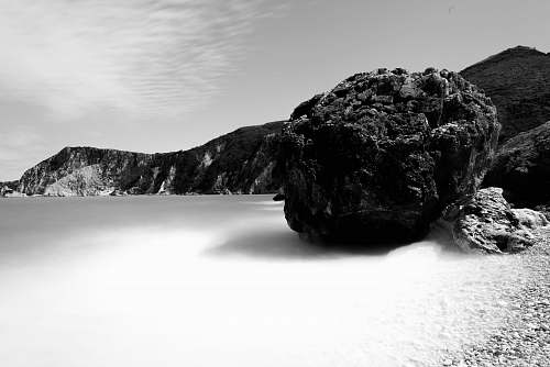 mountain grayscale photo of coastline surrounded with rocky cliffs rock