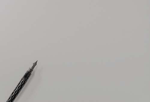 grey grayscale photo of fountain pen flying